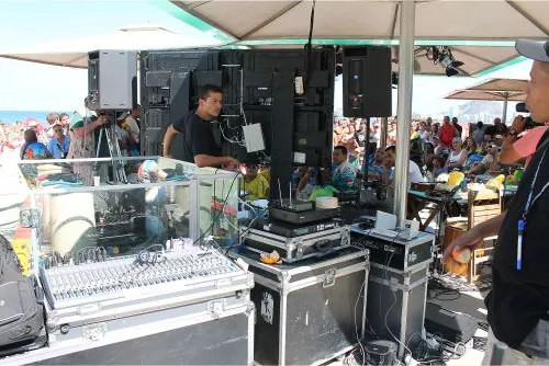 Mesa de som em operação sob tenda, evento na praia